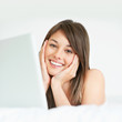 Smiling young lady lying with a laptop