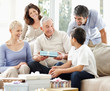 Grandfather gifting his grandson in the presence of their family