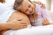 Foto: Excited young girl listening to her pregnant mother belly Excited young girl listening to her pregnant mother belly