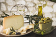 Olives, cheese, crackers & olive oil on table out of doors