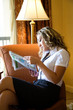 Young pretty female reading a newspaper in a hotel room