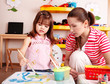 Child with teacher draw paints in play room.