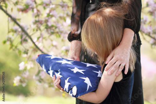 Photo: Child Holding a Parent's Folded American Flag Child Holding a Parent's Folded American Flag