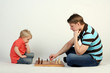 Young father playing chess with his little cute son
