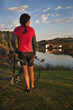 Female cyclist by vineyard lake at sundown. Tasmania