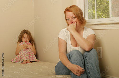 Photo: Mom and daughter sitting on an old mattress looking concerned Mom and daughter sitting on an old mattress looking concerned