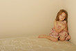 Sad girl sitting on an old mattress holding bear
