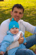 The daddy with the baby sits in park on a grass The daddy with the baby sits in park on a grass