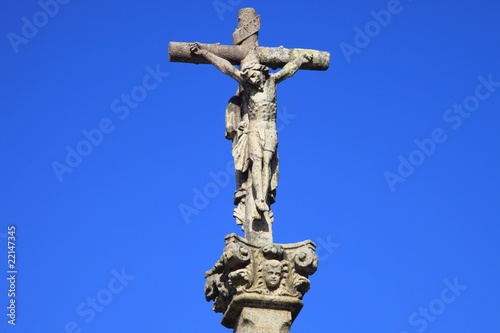 Jesus Christus am Kreuz, Steinfigur vor blauem Himmel Jesus Christus am Kreuz, Steinfigur vor blauem Himmel