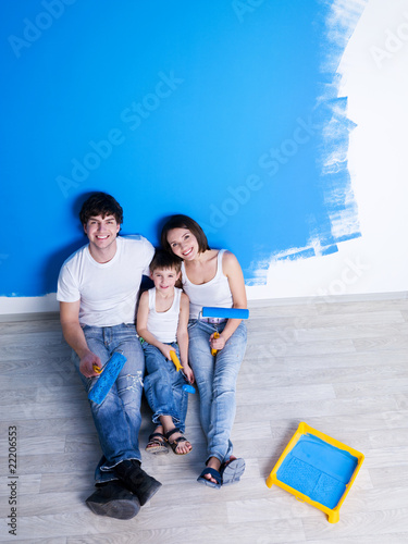 Photo: Painting the wall by happy family Painting the wall by happy family