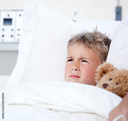 Photo: Sick little boy lying in a hospital bed Sick little boy lying in a hospital bed