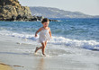 child in a white dress running through the waves