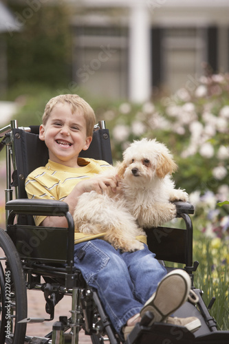 Foto: Young boy in wheelchair smiling and holding dog Young boy in wheelchair smiling and holding dog