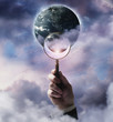Businessman holding magnifying glass up to planet Earth