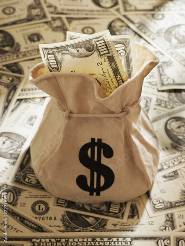 Photo: Bag of US Dollars on pile of US Dollars Bag of US Dollars on pile of US Dollars