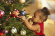 African baby girl touching Christmas tree