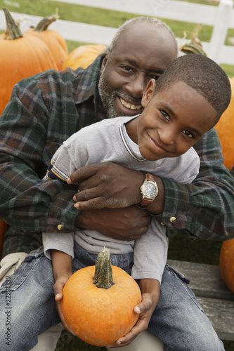 Photo: Portrait of African father and son holding pumpkin Portrait of African father and son holding pumpkin