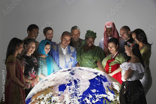 Foto: Multi-ethnic people in traditional dress looking at globe Multi-ethnic people in traditional dress looking at globe