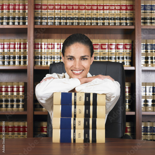 Photo: Hispanic female lawyer leaning on stack of books Hispanic female lawyer leaning on stack of books