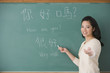 Asian female teacher writing Chinese on blackboard