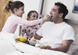 Girls giving father breakfast in bed