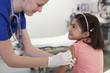 Medical professional preparing girl's arm for shot