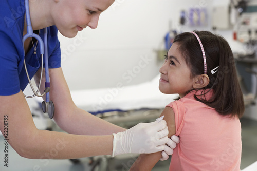 Photo: Medical professional preparing girl's arm for shot Medical professional preparing girl's arm for shot