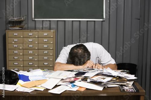 Photo: Senior Asian businessman resting head on cluttered desk Senior Asian businessman resting head on cluttered desk