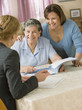 Senior Hispanic woman discussing paperwork with businesswoman