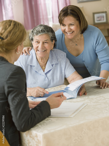 Photo: Senior Hispanic woman discussing paperwork with businesswoman Senior Hispanic woman discussing paperwork with businesswoman