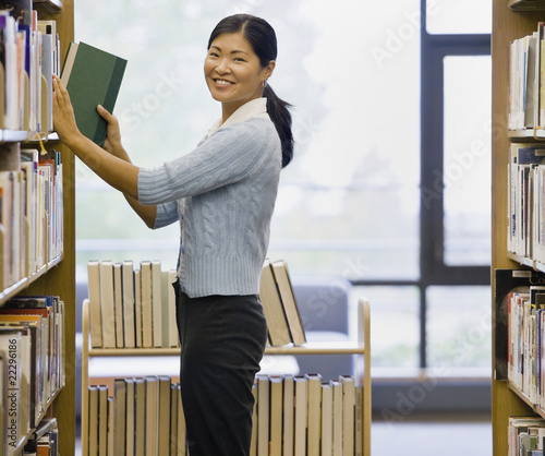 Photo: Asian woman shelving library books Asian woman shelving library books