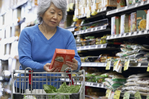 Photo: Senior Asian woman reading label at grocery store Senior Asian woman reading label at grocery store