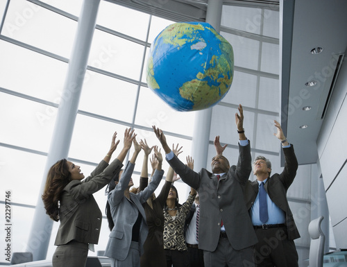 Photo: Multi-ethnic businesspeople playing with globe ball Multi-ethnic businesspeople playing with globe ball
