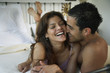 Hispanic couple laughing on bed