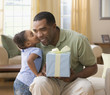 Mixed Race girl kissing father holding gift