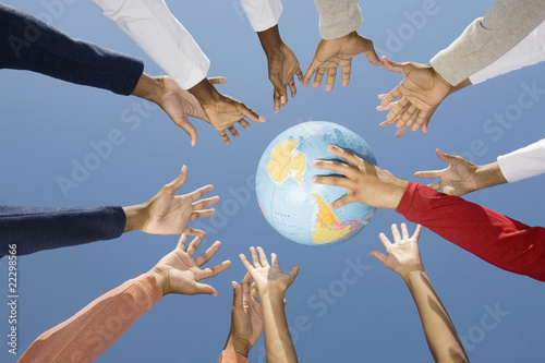 Photo: Multi-ethnic hands reaching for globe ball Multi-ethnic hands reaching for globe ball