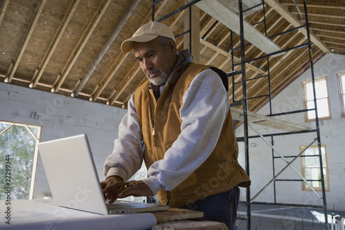 Photo: Hispanic architect typing on laptop Hispanic architect typing on laptop