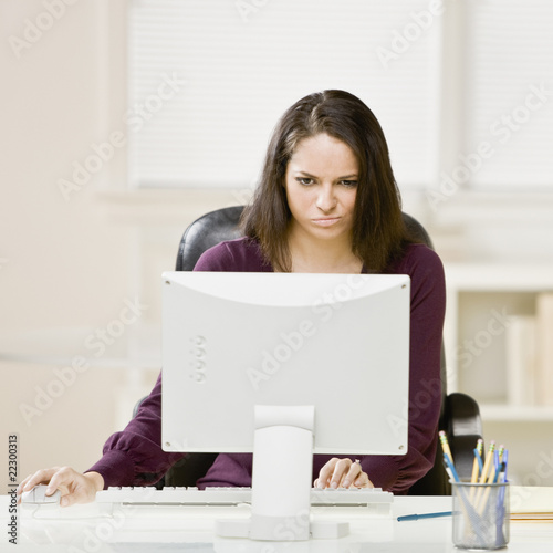 Photo: Hispanic businesswoman looking at computer Hispanic businesswoman looking at computer