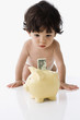 Hispanic baby looking at money in piggy bank