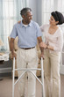 Middle Eastern woman helping man use walker