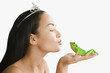 Mixed race woman with tiara kissing toy frog