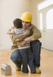 Hispanic construction worker hugging son