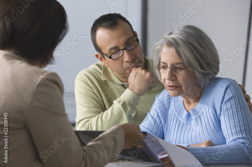 Photo: Hispanic man helping mother read sales contract Hispanic man helping mother read sales contract