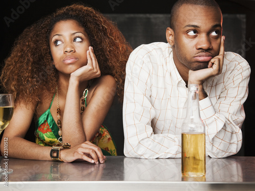 Photo: Couple sitting at bar and looking irritated Couple sitting at bar and looking irritated