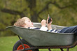 Photo: Young Boy Laying Wheelbarrow Using Smart Mobile Phone Young Boy Laying Wheelbarrow Using Smart Mobile Phone