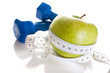 Dumbbells, green apple and measure tape isolated on white