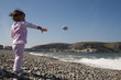 Little girl happily throwing pebbles into the sea