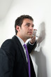 junger business mann hört an einer wand mit glas