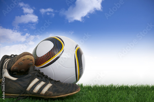 Foto: Pair soccer shoes and football on grass in front of blue sky Pair soccer shoes and football on grass in front of blue sky
