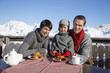 Couple and daughter eating on balcony at ski resort